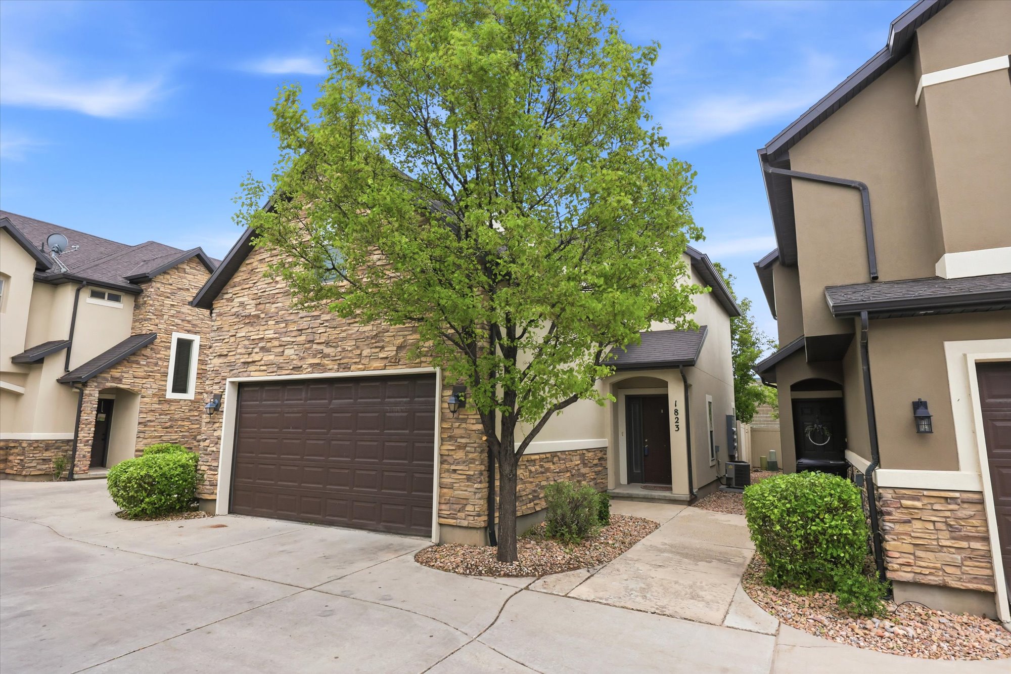 View of front of property with stone siding, stucco siding, and concrete driveway