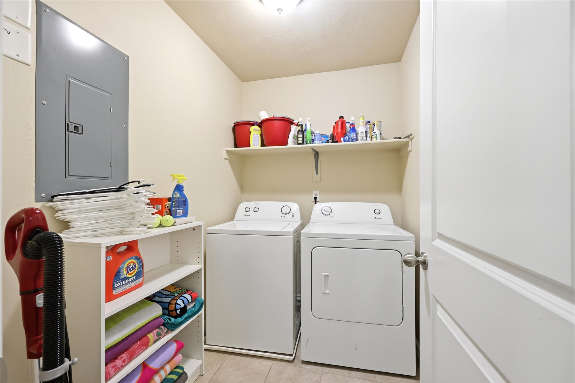 Laundry area featuring electric panel, washer and clothes dryer, and light tile patterned flooring