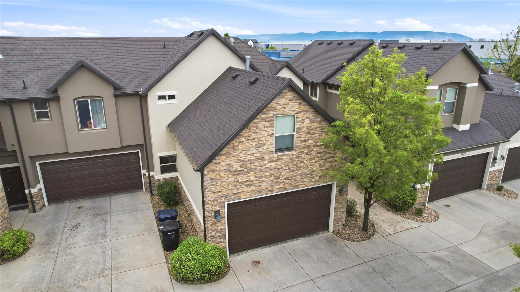 View of front of property with stucco siding, a garage, and stone siding