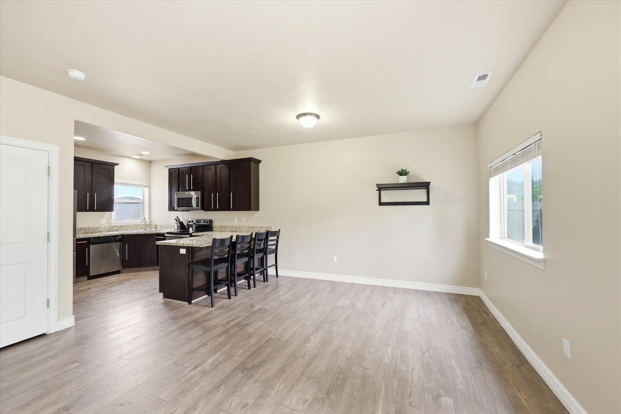 Kitchen with a breakfast bar area, dark wood finish cabinetry, a peninsula, light wood-style floors, and stainless steel appliances