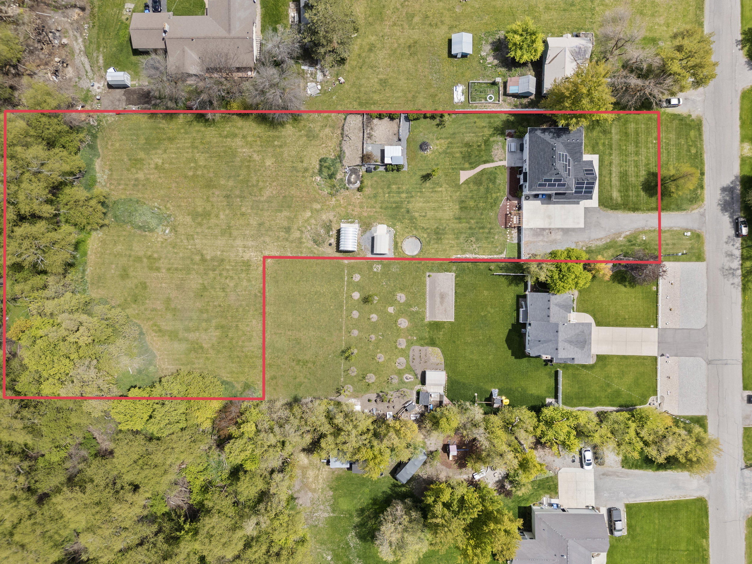 Expansive property featuring a large open lot, mature trees along the perimeter, and two distinct sections of land