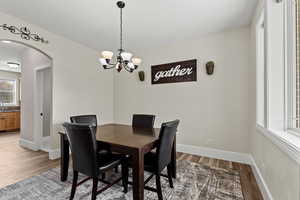 Dining space featuring arched walkways, a chandelier, and light wood-style flooring