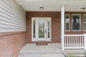 Doorway to property featuring brick siding and a porch