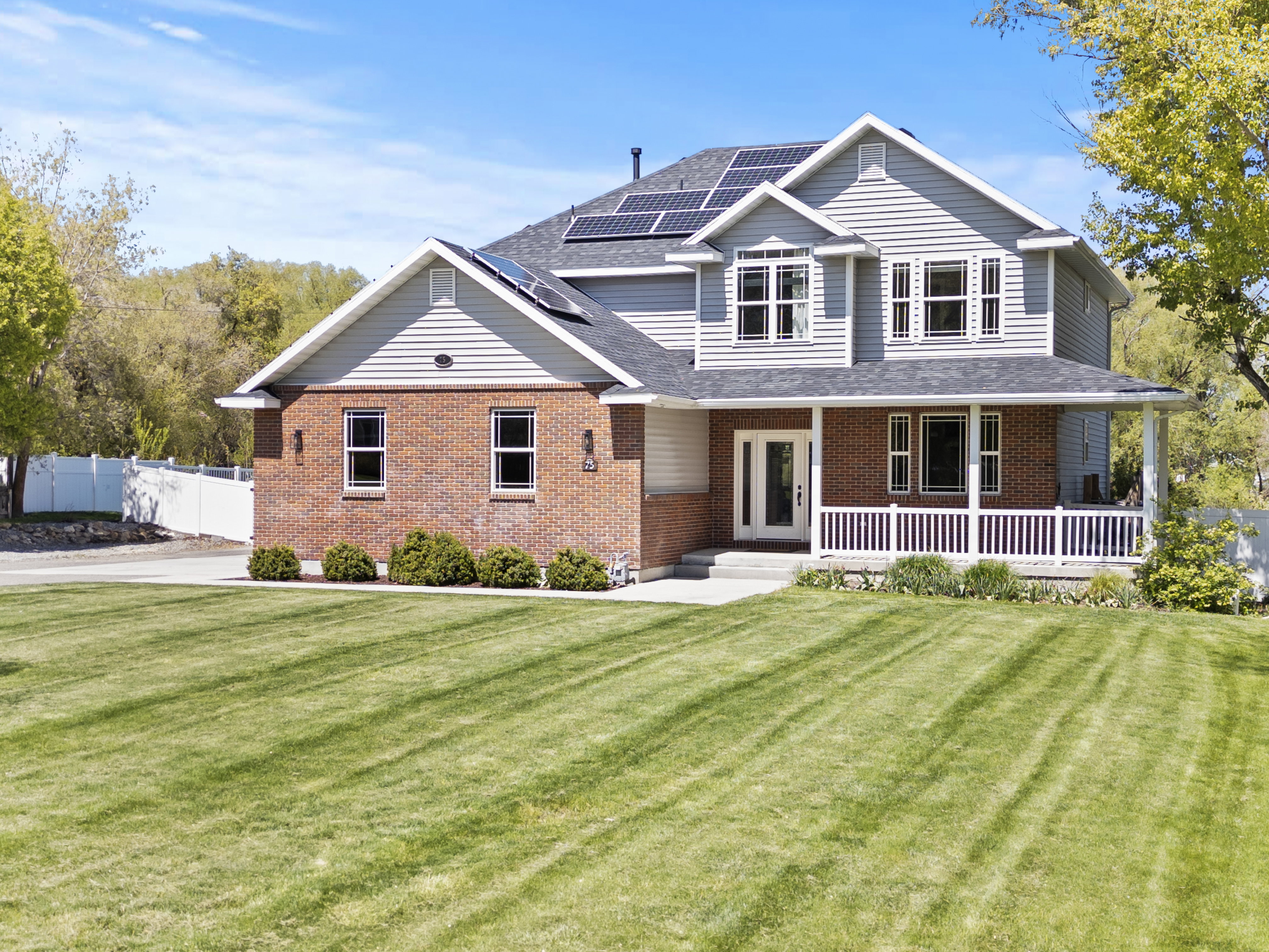View of front of house featuring roof mounted solar panels, a porch, brick siding, and a shingled roof