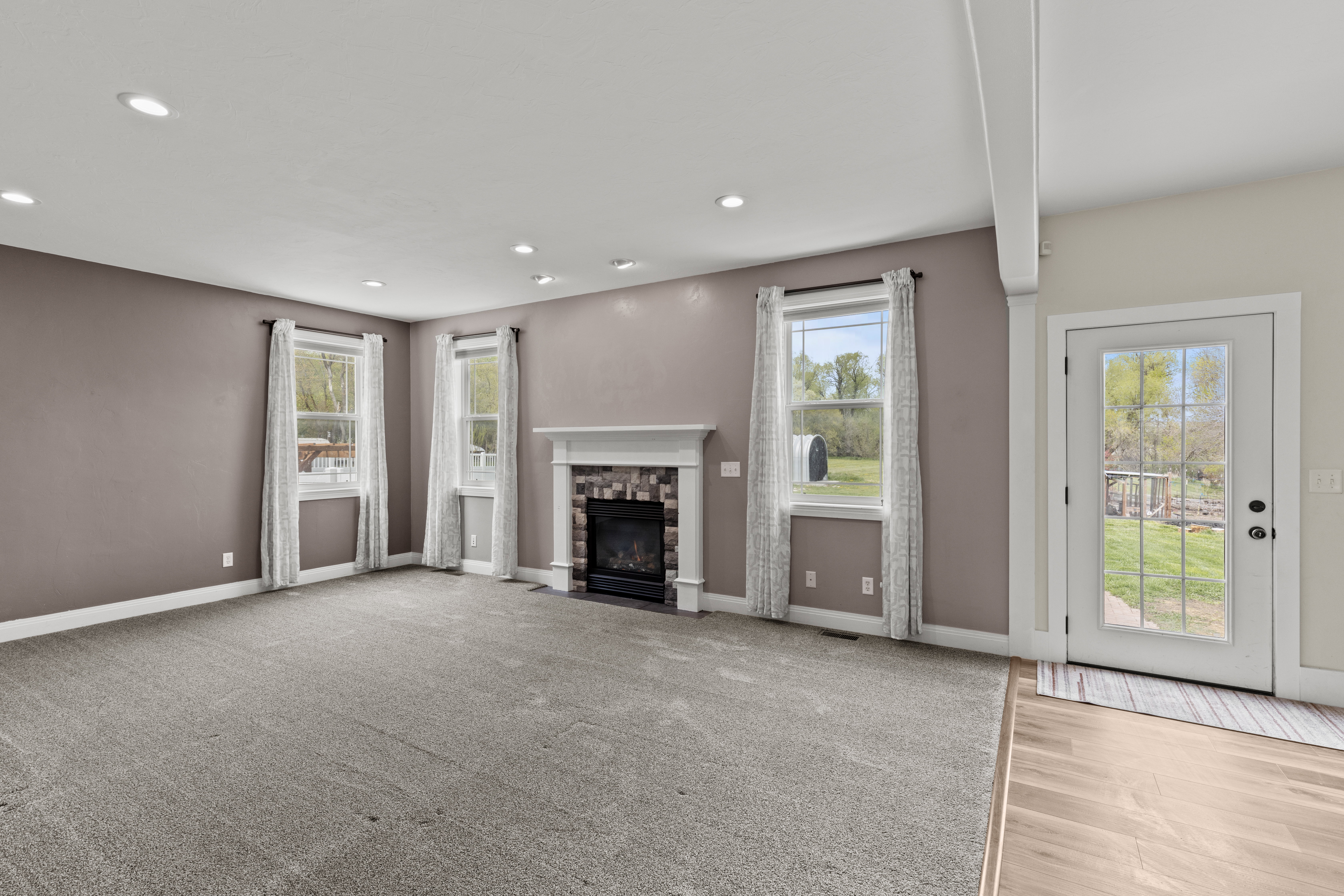 Unfurnished living room featuring a fireplace, recessed lighting, and light carpet