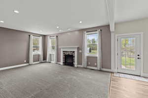 Unfurnished living room featuring a fireplace, recessed lighting, and light carpet