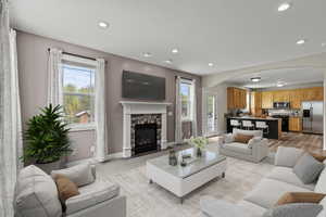 Living area featuring arched walkways, a fireplace, recessed lighting, and light wood-style flooring