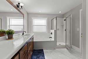 Bathroom featuring a shower stall, a garden tub, vanity, recessed lighting, and light marble finish floors