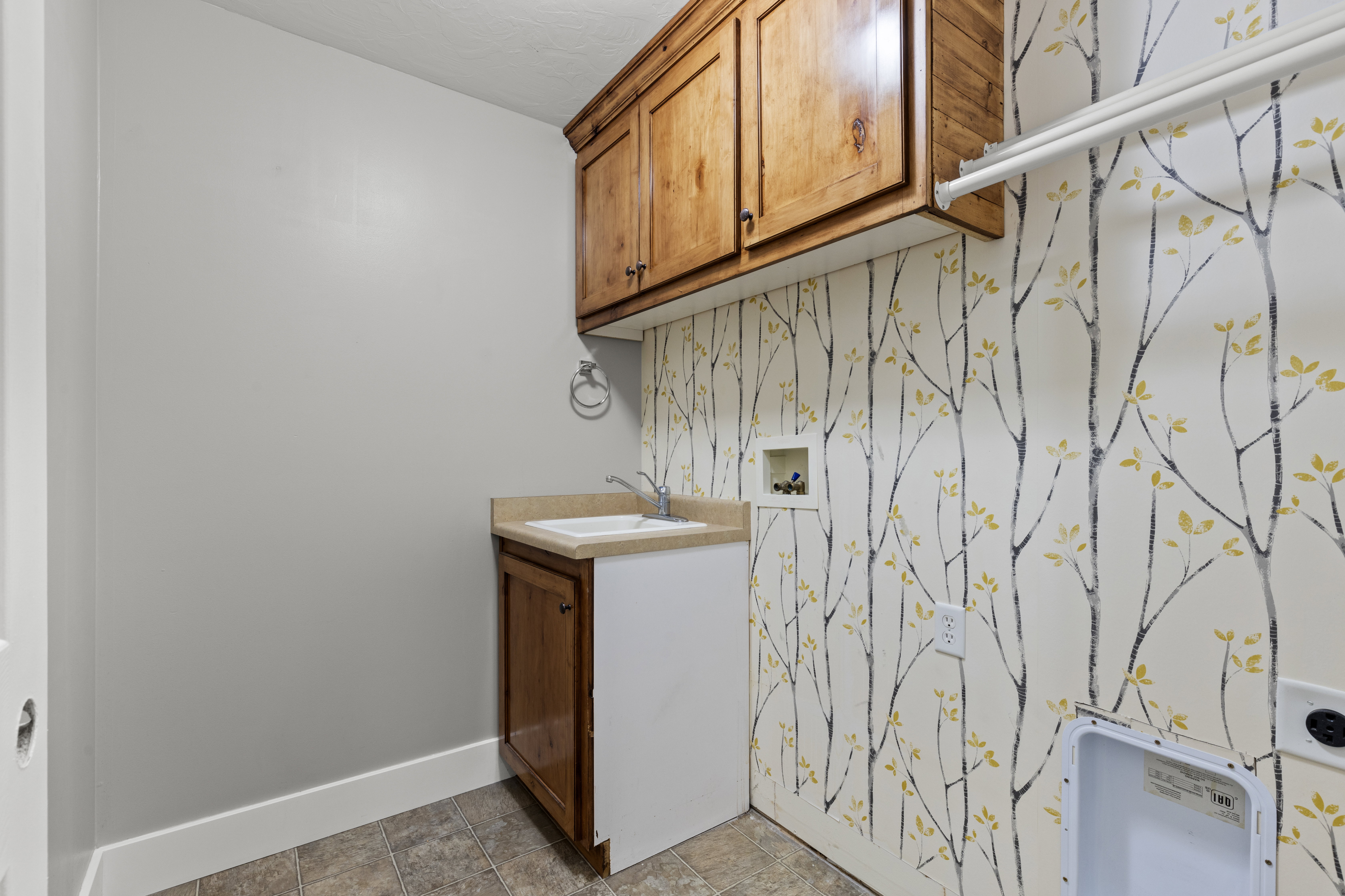 Laundry room with cabinet space, washer hookup, wallpapered walls, and an accent wall