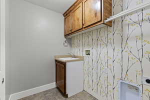 Laundry room with cabinet space, washer hookup, wallpapered walls, and an accent wall