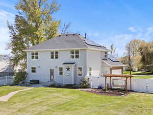 Rear view of house with a gate, a fenced backyard, roof mounted solar panels, an attached garage, and roof with shingles
