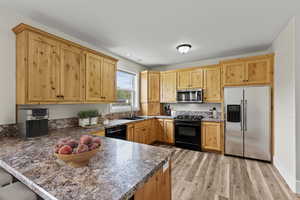 Kitchen with black appliances, a kitchen bar, a peninsula, light wood-style flooring, and light wood finish cabinetry