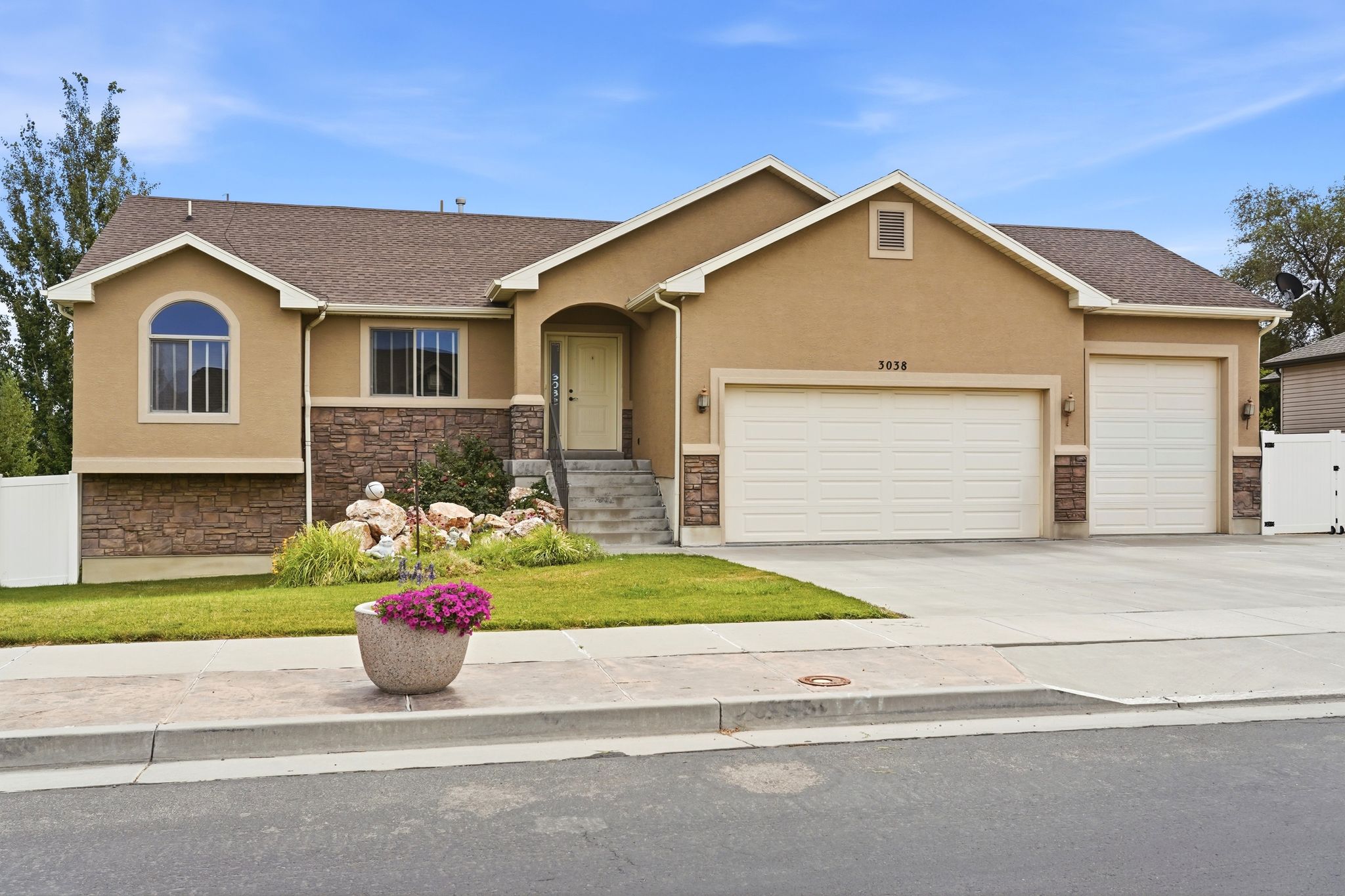 Stucco exterior with stone accenting, featuring an arched window and two-car garage