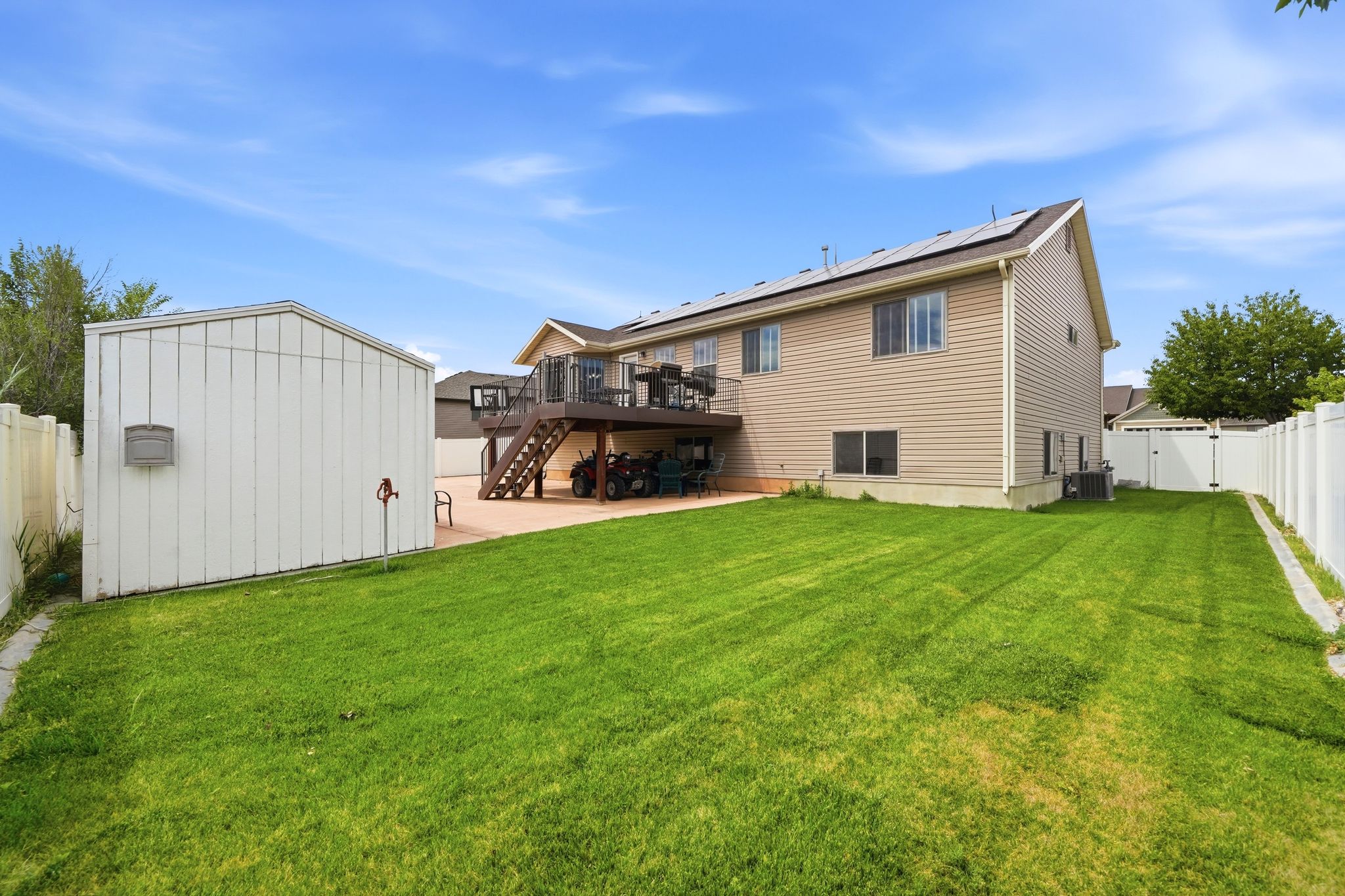 Expansive rear yard featuring a manicured lawn, a two-story deck, and a detached storage shed