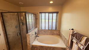 Bathroom with a marble finish shower, a bath, and recessed lighting