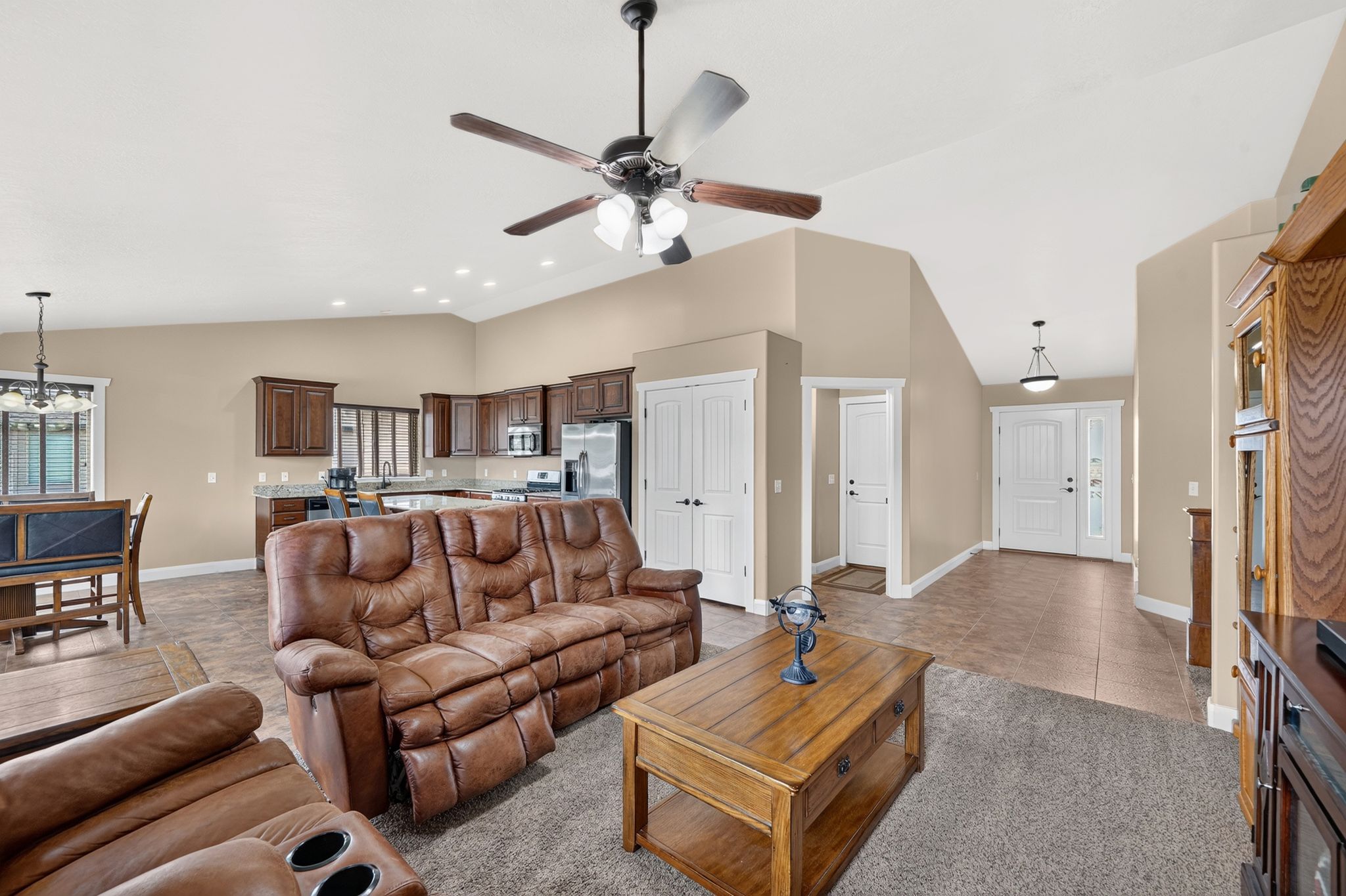 Open-concept living area featuring vaulted ceilings, recessed lighting, and a ceiling fan