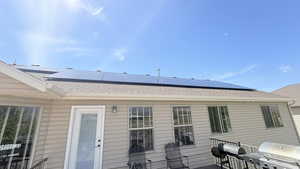 Rear view of property featuring solar panels and a shingled roof