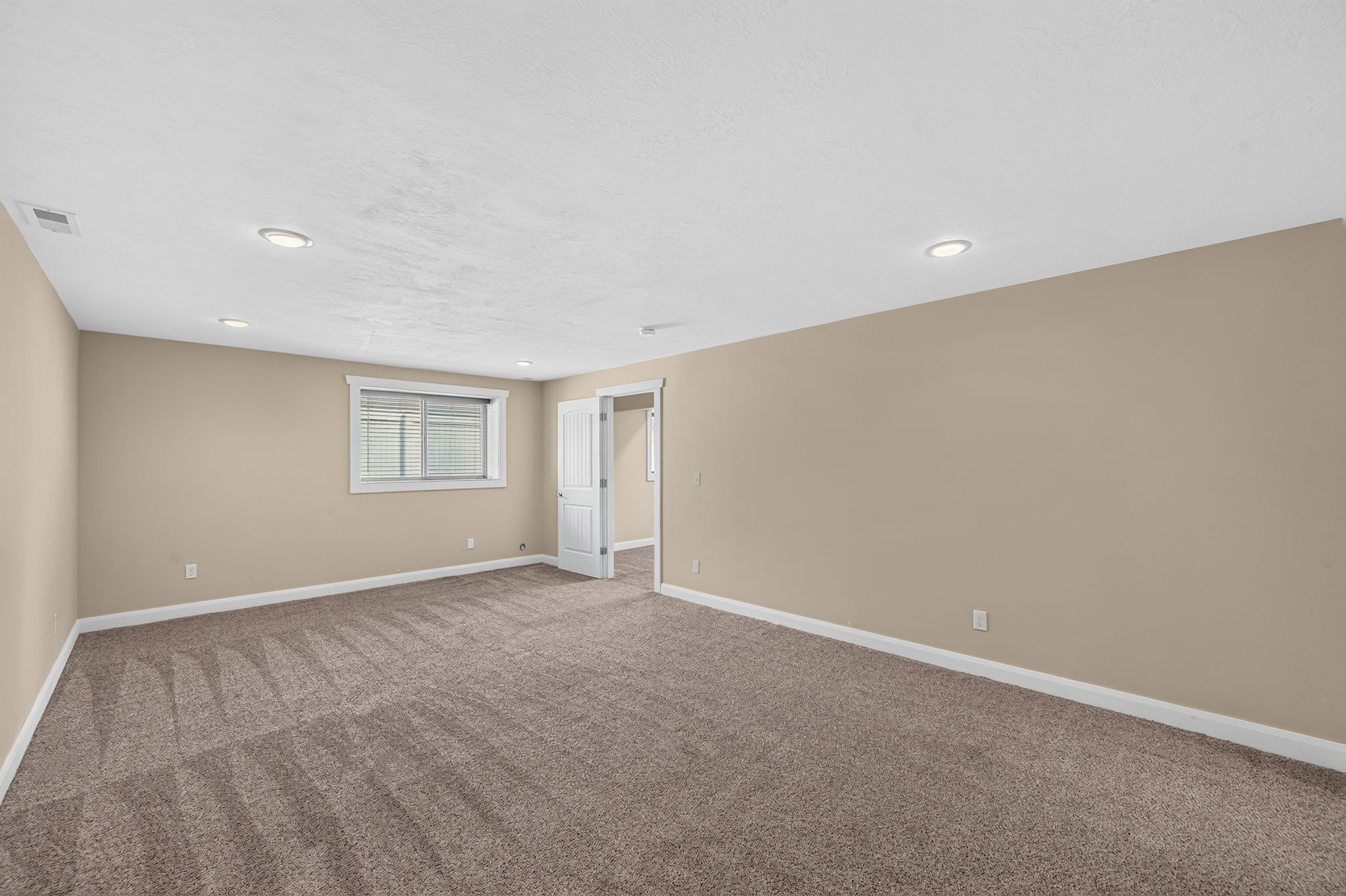 Spacious room featuring neutral-toned walls, recessed lighting, and soft pile carpet flooring
