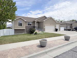 Single story home featuring stucco siding, a gate, stone siding, an attached garage, and concrete driveway