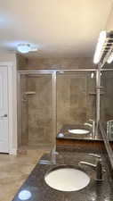 Full bathroom featuring double vanity, a stall shower with 2 heads, and light tile patterned floors
