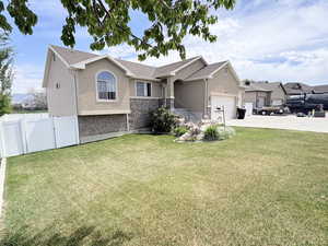 Single story home featuring a front lawn, stucco siding, stone siding, and concrete driveway