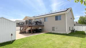 Rear view of house featuring a gate, a deck, solar panels, and a storage shed
