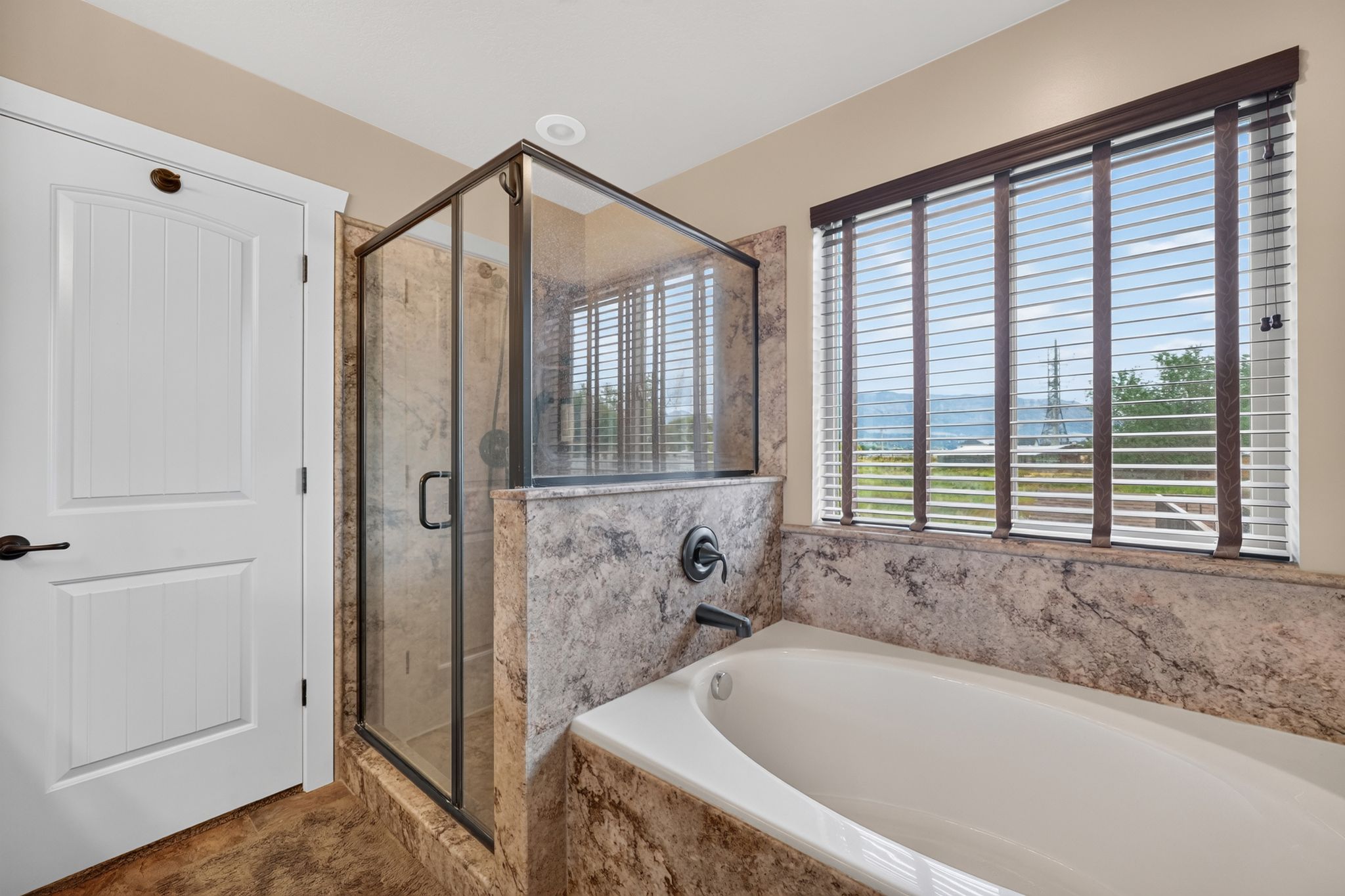 Built-in soaking tub and glass-enclosed shower with stone surround