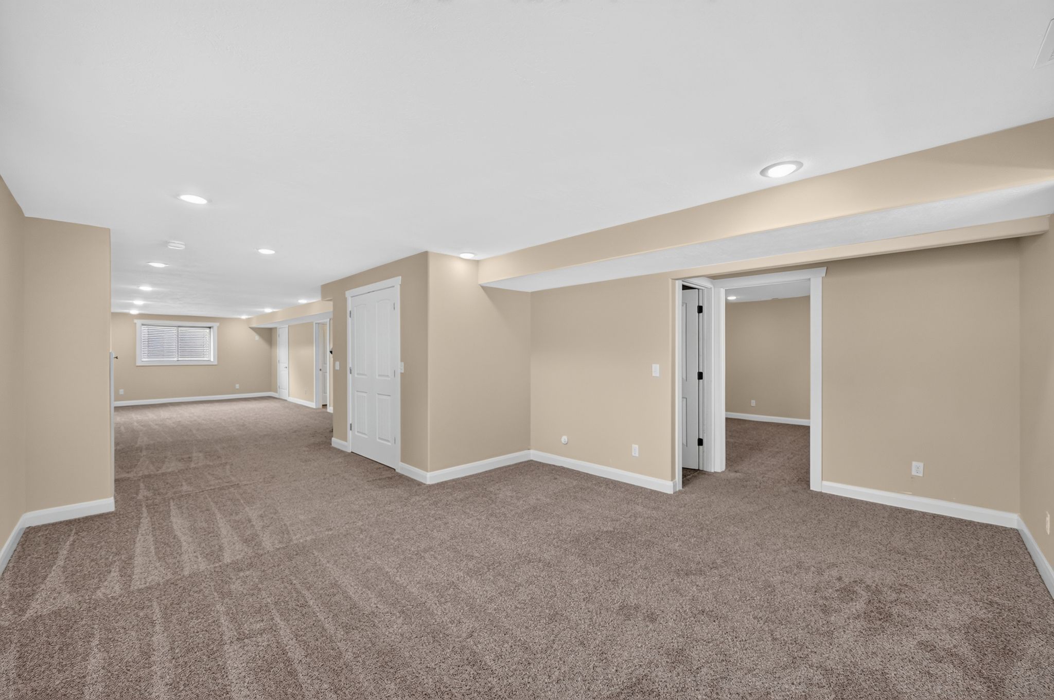 Spacious carpeted room featuring recessed lighting, a neutral color palette, white trim, and multiple doorways