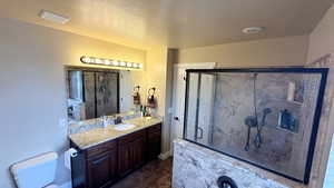 Bathroom with a marble finish shower, vanity, a textured ceiling, and dark wood-style flooring