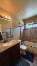 Bathroom with vanity, a textured ceiling, and bath / shower combo with glass door