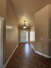 Doorway with baseboards and lofted ceiling