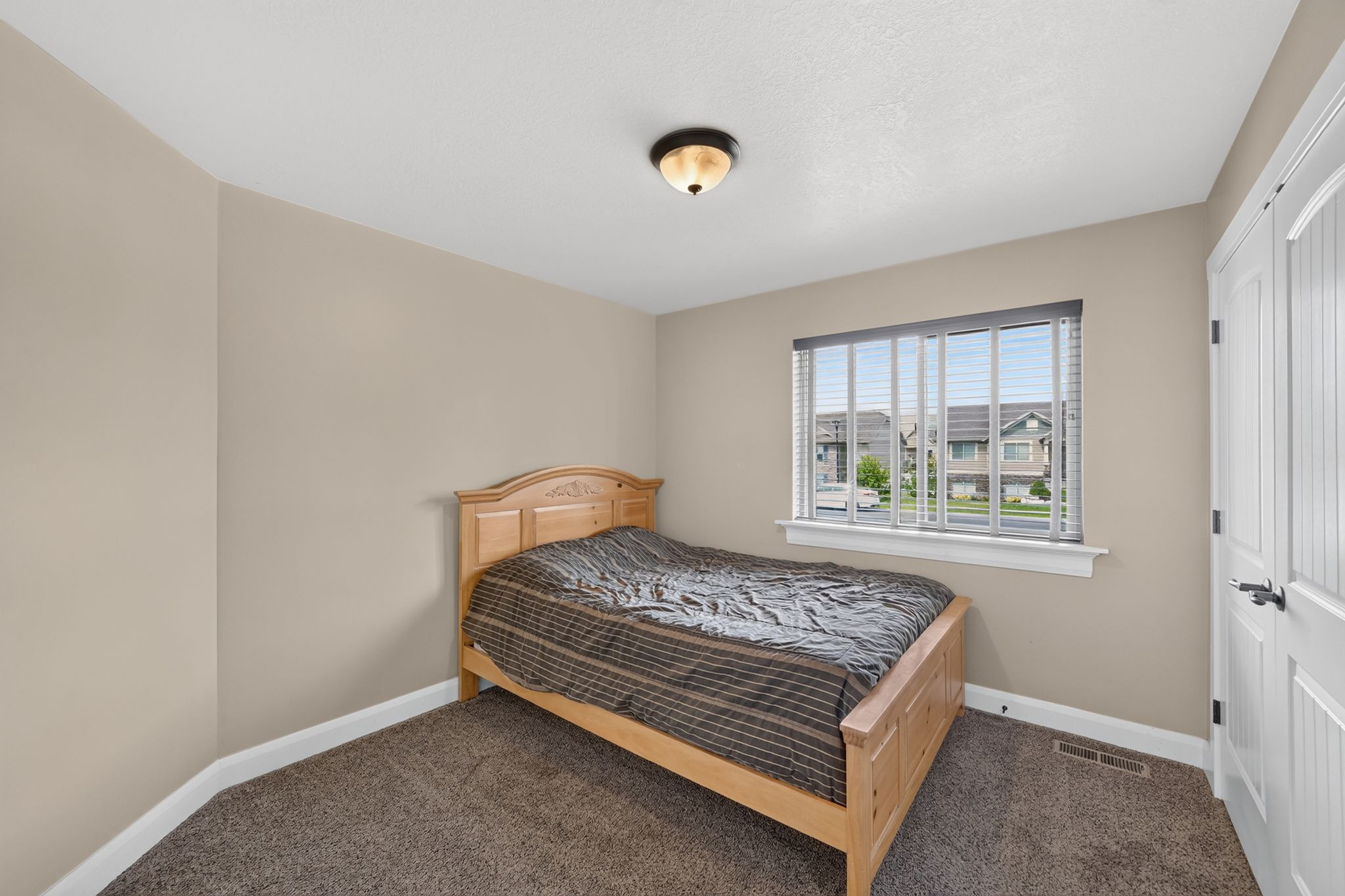 Carpeted room featuring neutral wall paint, a window with blinds, and white trim
