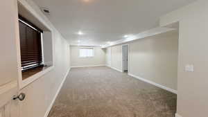 Empty room not staged -Below grade area featuring light carpet and baseboards