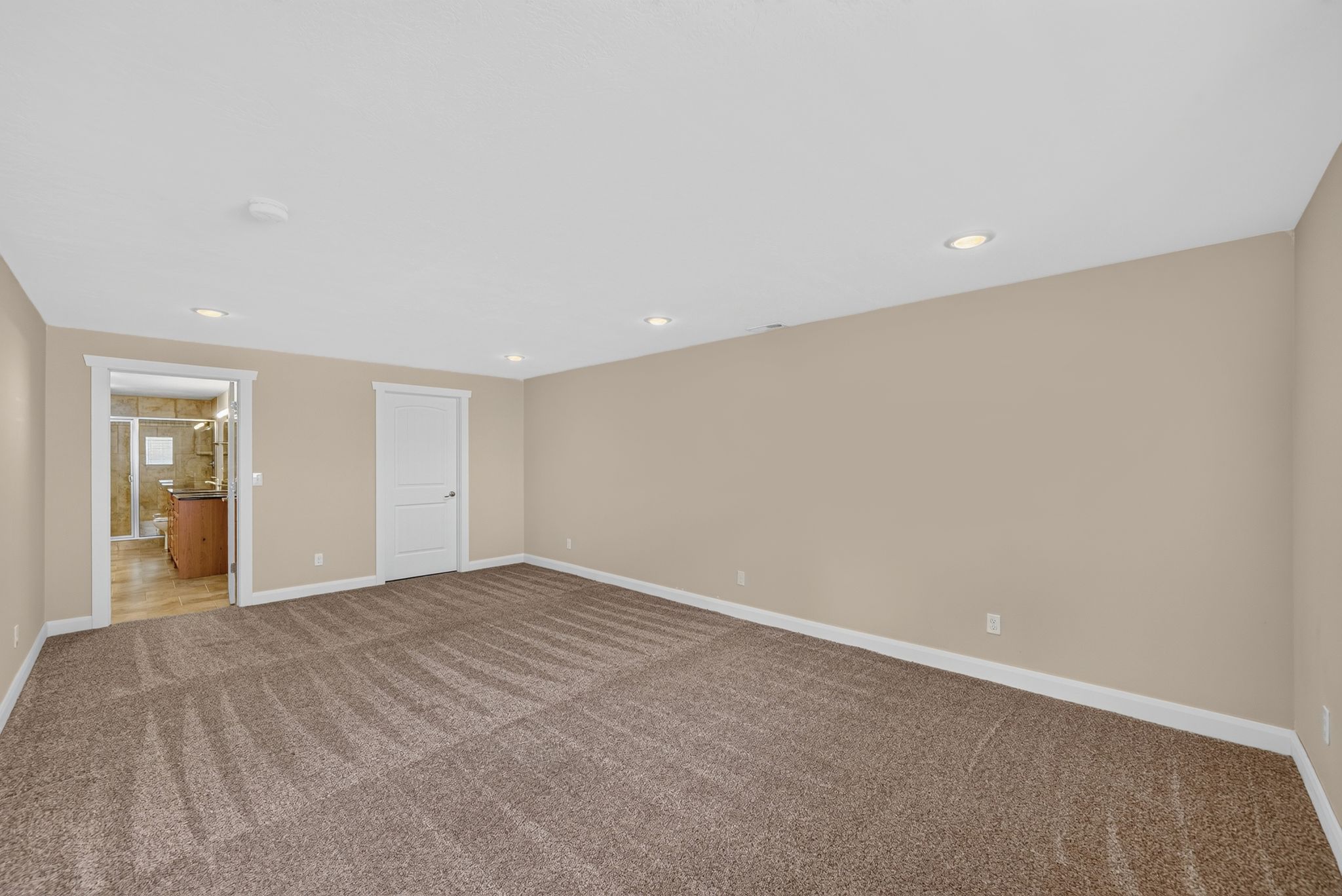 Spacious room with plush carpeting, recessed lighting, neutral wall tones, and white trim