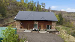 Rear view of house featuring stone siding, a metal roof, and a porch