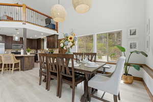 Dining room with light wood-style floors, a high ceiling, and recessed lighting