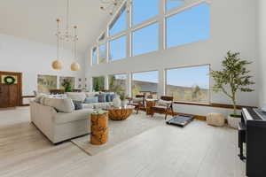 Living room featuring light wood-style flooring, hanging lights, and lofted ceiling