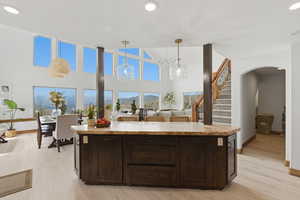 Kitchen with dark wood finish cabinetry, decorative light fixtures, a high ceiling, light wood-style floors, and a mountain view