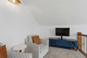 Sitting room with lofted ceiling and carpet flooring