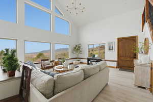 Living room with light wood-style flooring, hanging lights, vaulted ceiling, and a mountain view