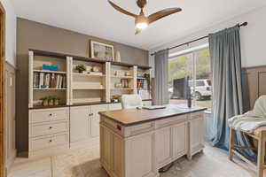 Office area featuring a ceiling fan, a wainscoted wall, and light wood-style floors