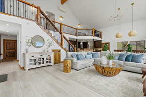 Living room with light wood-type flooring, suspended lighting, and lofted ceiling