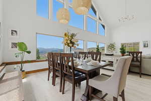 Dining room featuring light wood-style flooring, a mountain view, suspended lighting, and lofted ceiling