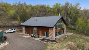 View of front of house with stone siding, a porch, a metal roof, and gravel driveway