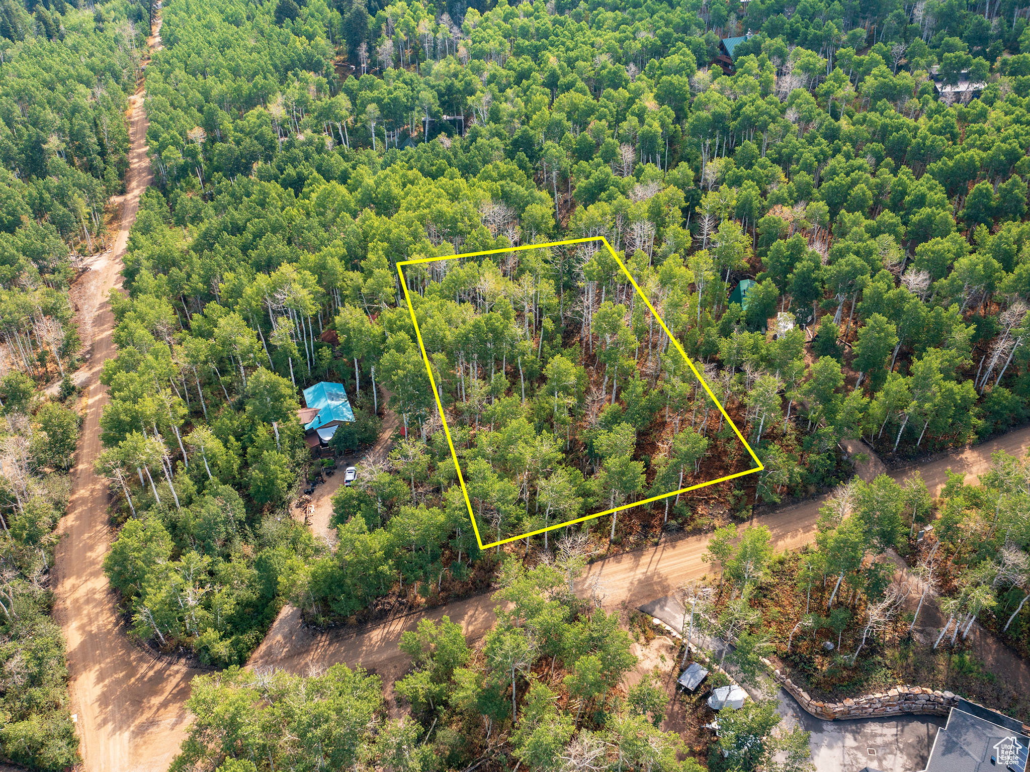Aerial view of property's location featuring property parcel outlined and a heavily wooded area