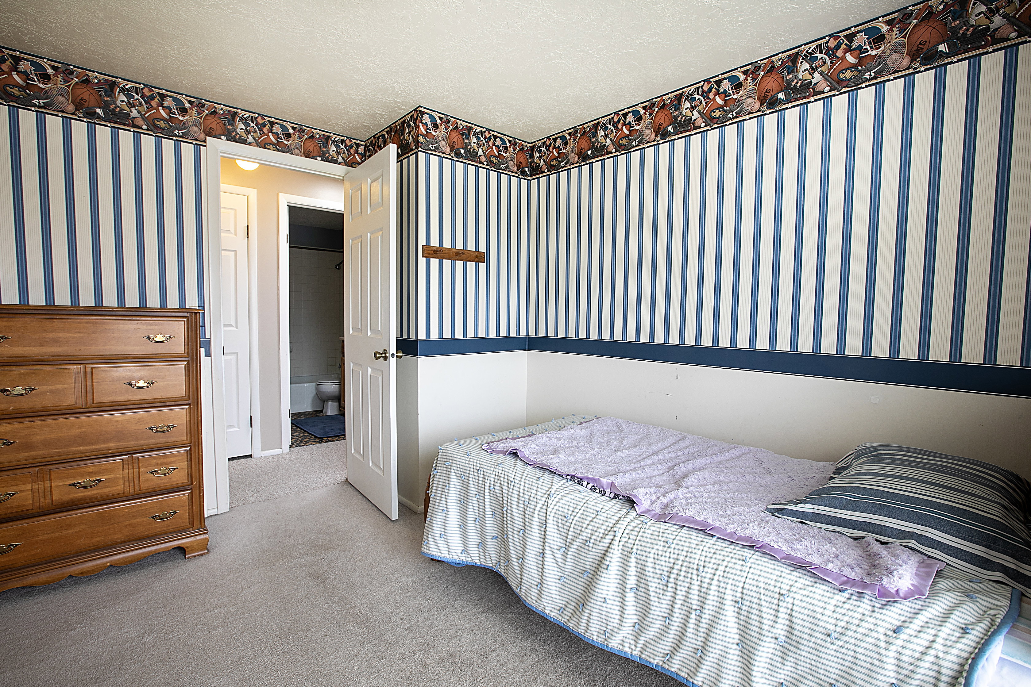 Carpeted bedroom featuring wallpapered walls and a textured ceiling