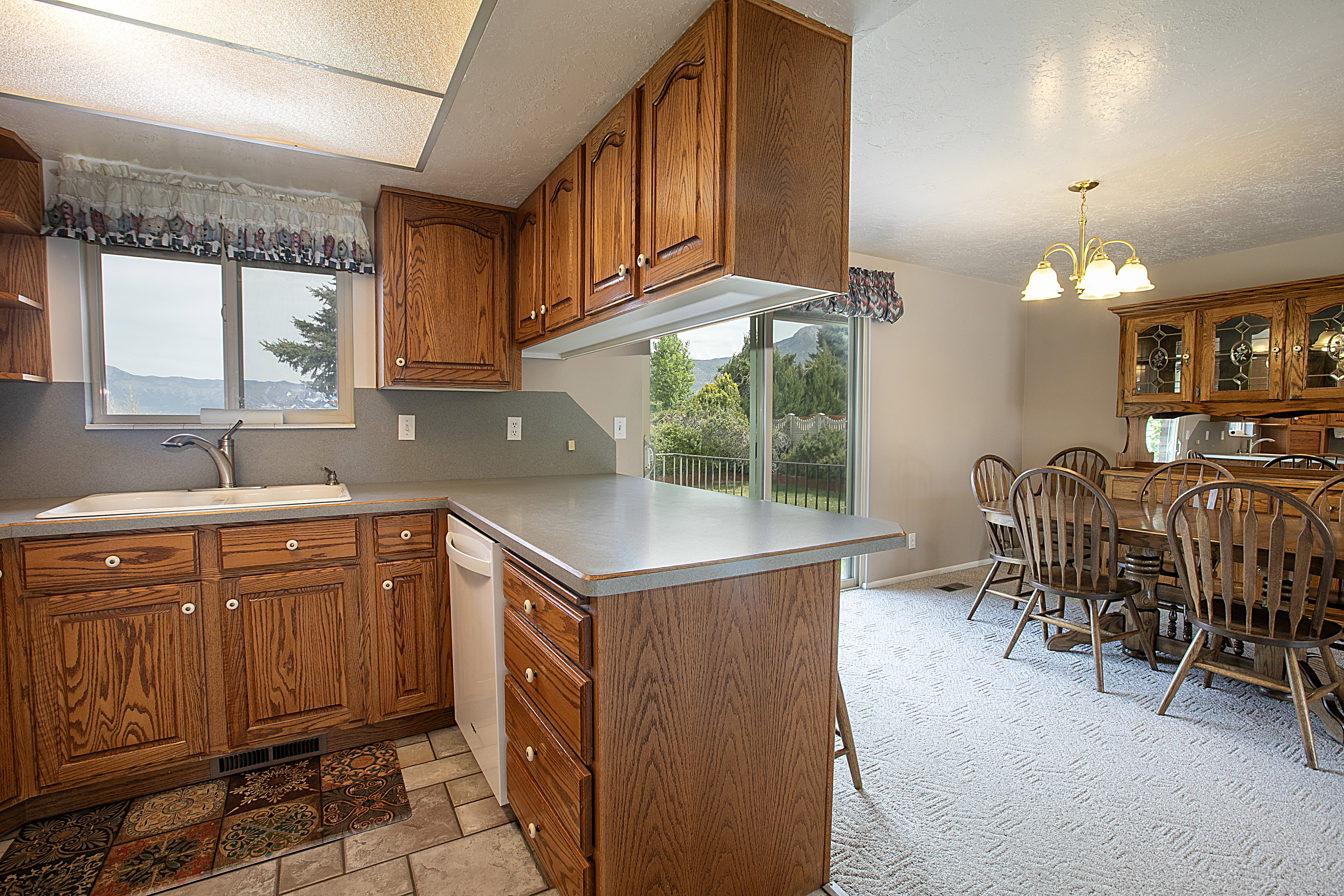 Kitchen with wood finish cabinets, a chandelier, a peninsula, light countertops, and a textured ceiling