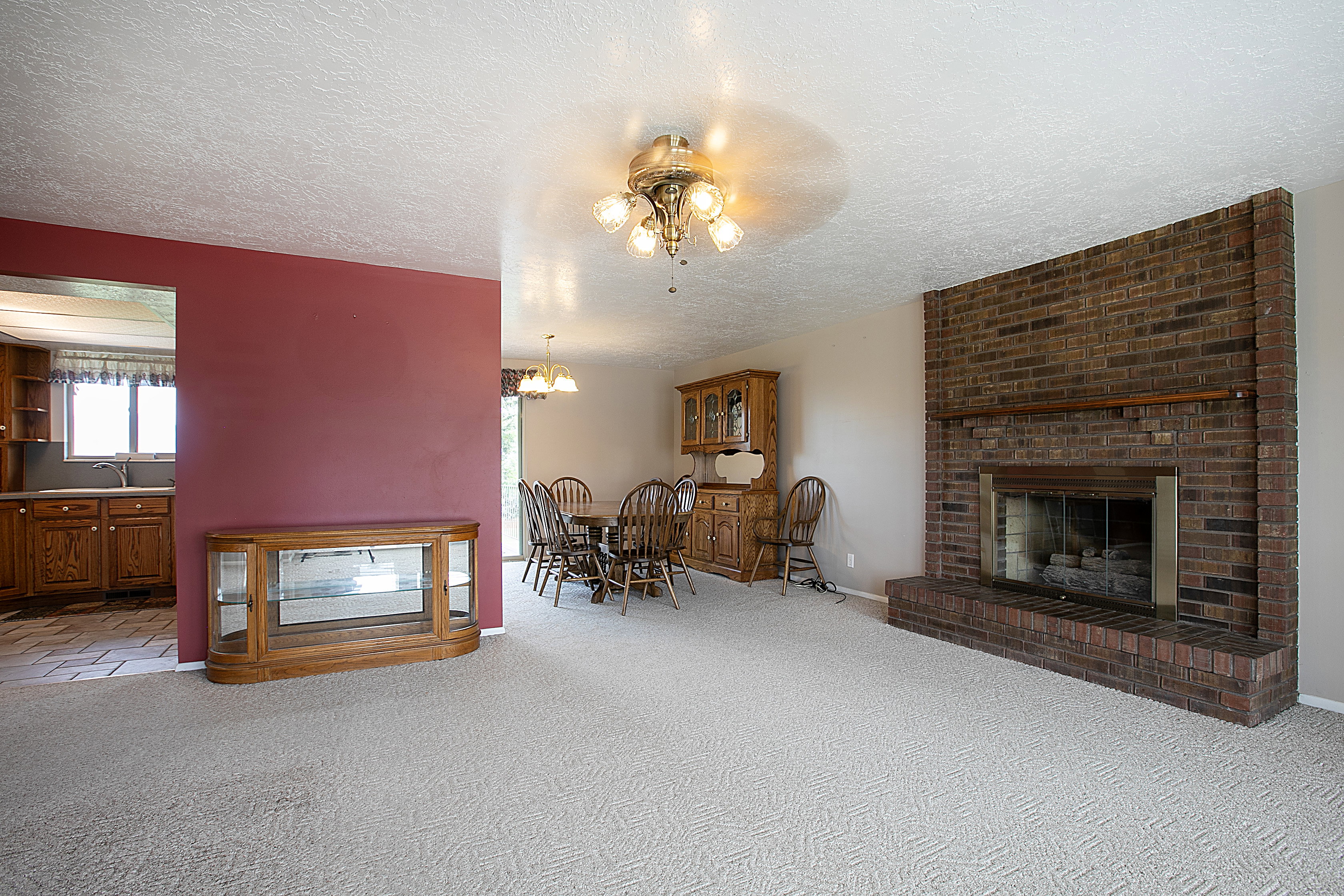 Living room with a fireplace, light colored carpet, a textured ceiling, and a chandelier