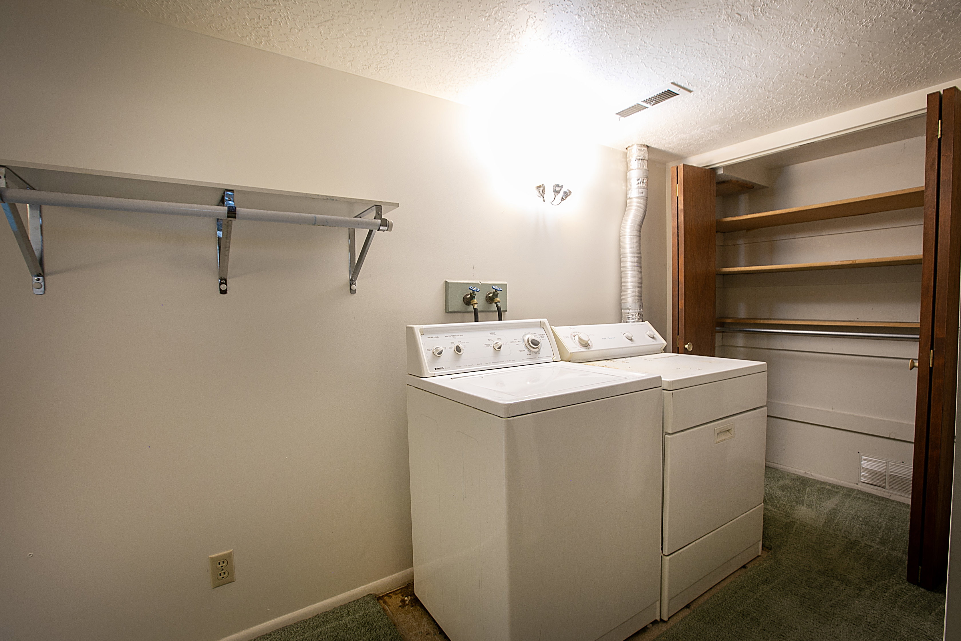 Laundry room with dark colored carpet, a textured ceiling, and washing machine and clothes dryer