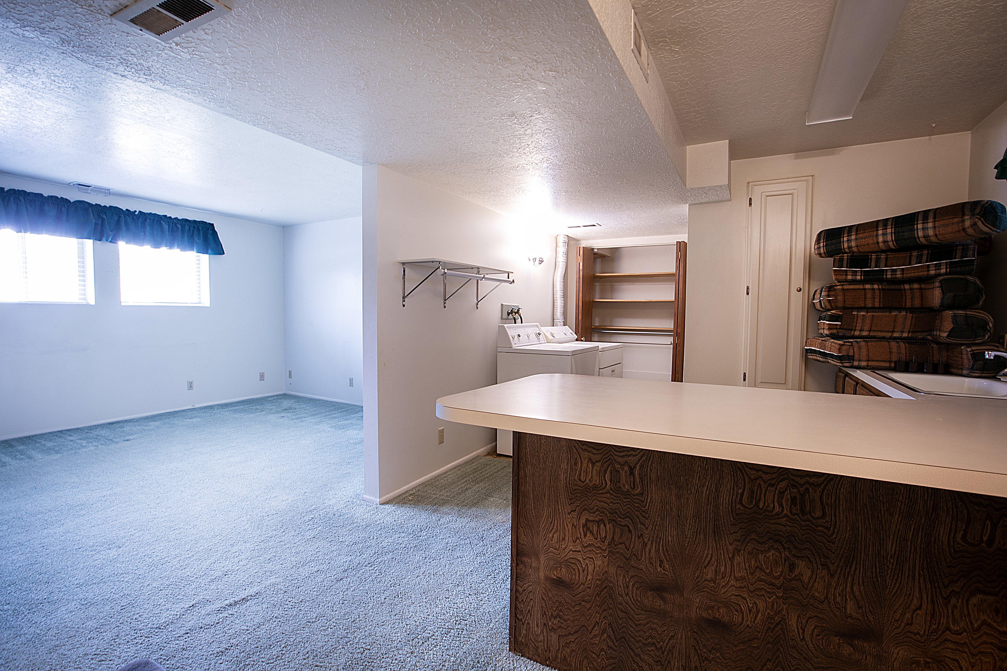 Kitchen with light countertops, light carpet, a textured ceiling, independent washer and dryer, and a peninsula